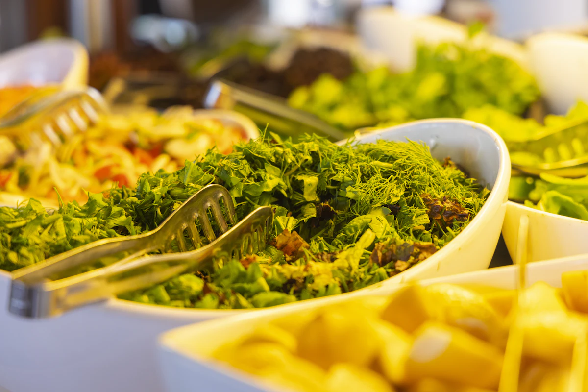 Buffet com travessas de saladas e acompanhamentos